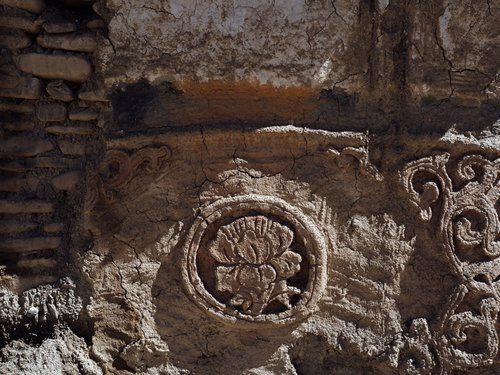 Carved mud-plaster ornament on a house façade — Dolpo vernacular craft using local river clay. Mud is also the primary thermal mass material.