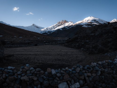 Pre-dawn light on the Dho Tarap fields and snow peaks. The valley faces south-southeast — the orientation that makes passive solar viable here.