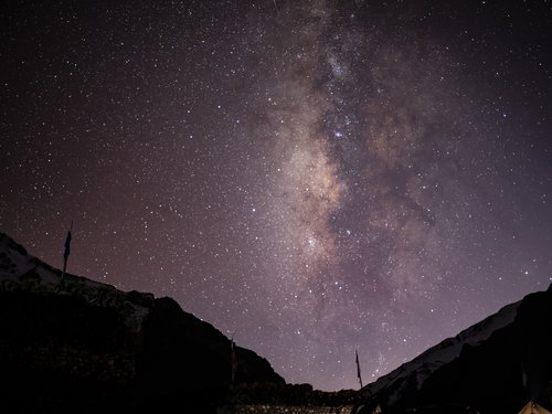 The Milky Way over Dho Tarap, prayer flags in silhouette. Low humidity and 3,900 m altitude give clear nights of exceptional transparency.