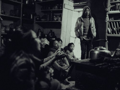 A local family gathered around the hearth in a traditional stone home, lower Dolpo. Open-fire cooking with no chimney stack is the norm.