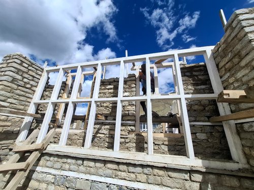 The south wall: the Trombe wall's glazing frame going up in front of the stone and mud mortar that will store the day's heat.
